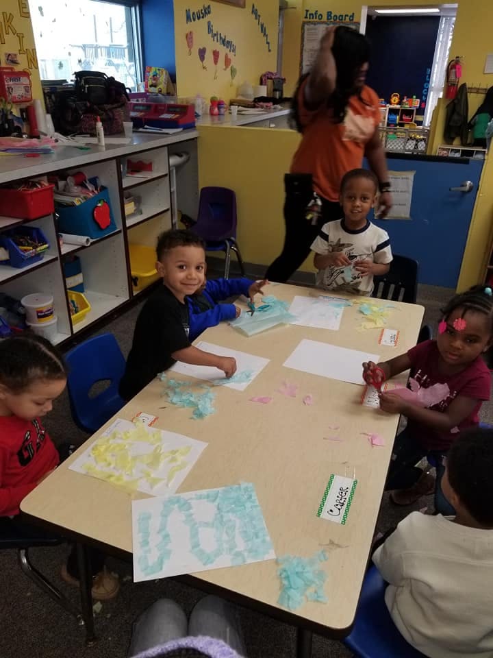 Children doing an art activity at a table in a classroom