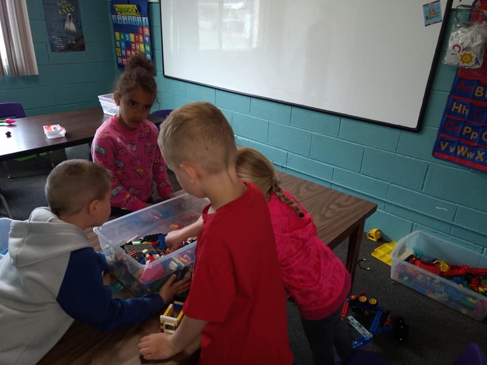 Four children playing with toys in a classroom