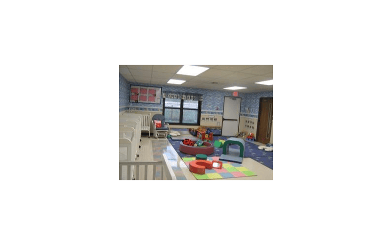 Classroom with multiple cribs, a rocking chair, and play mats on the floor