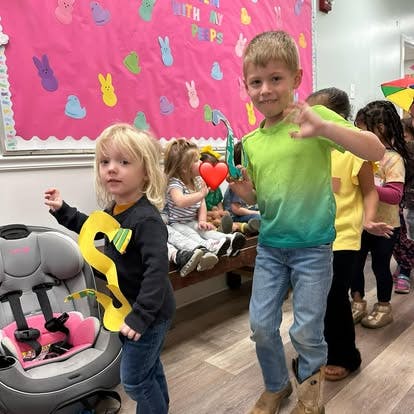 Children holding paper crafts in a classroom