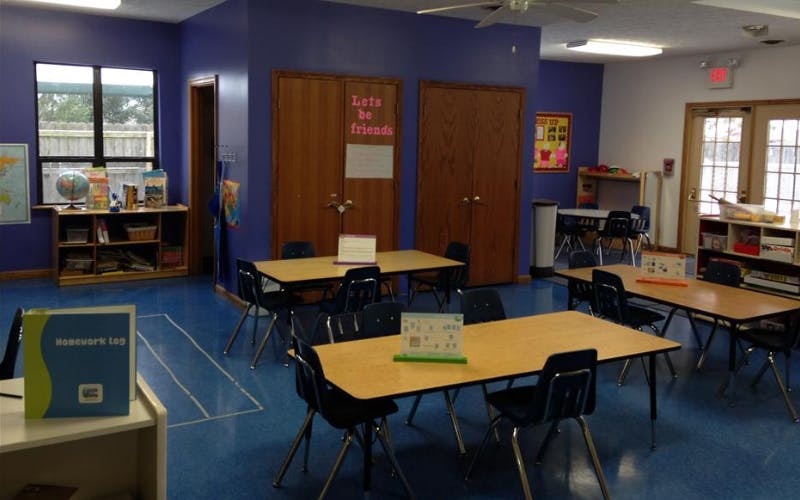 Classroom with small tables and chairs, "Lets be friends" sign on wall