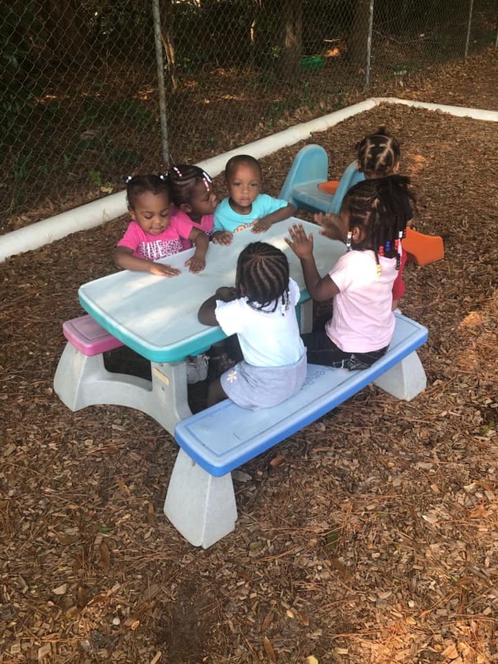 Children sitting around a small picnic table outdoors