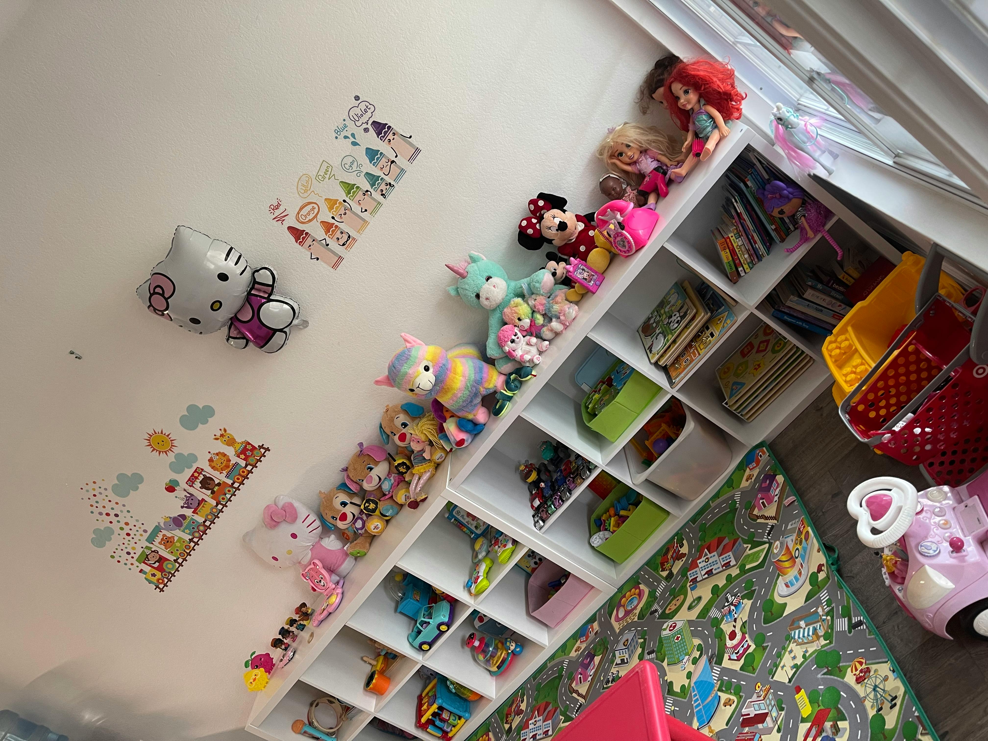 Wall with Hello Kitty decor and a white cubby shelf filled with toys