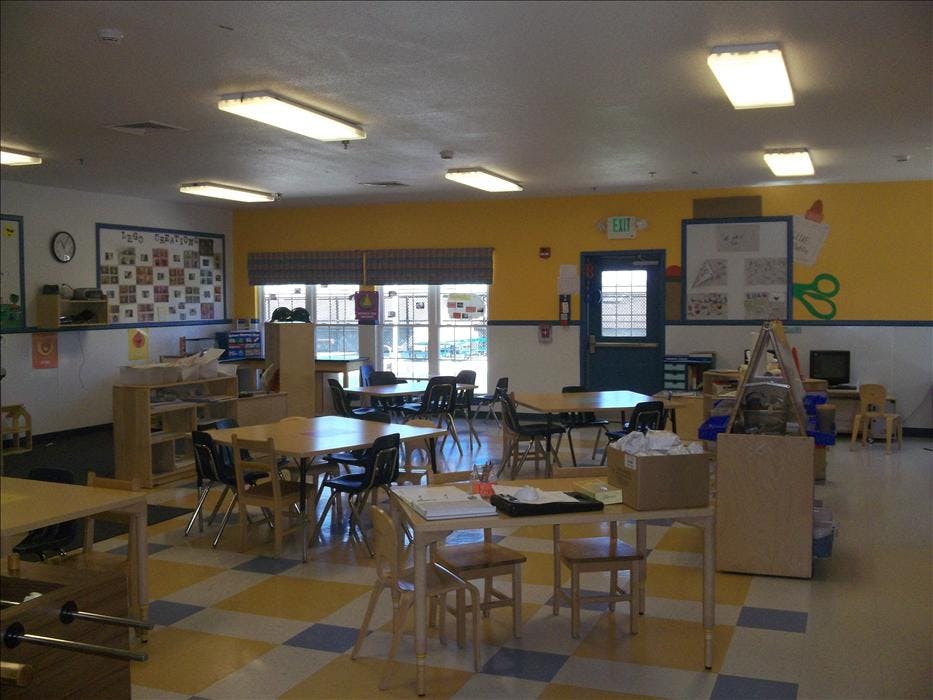 Empty classroom with small tables and chairs, yellow and blue walls