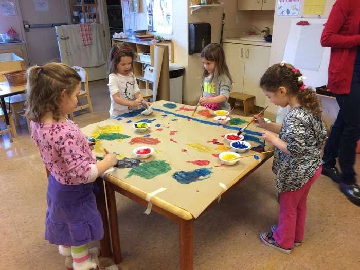 Four children painting at a table