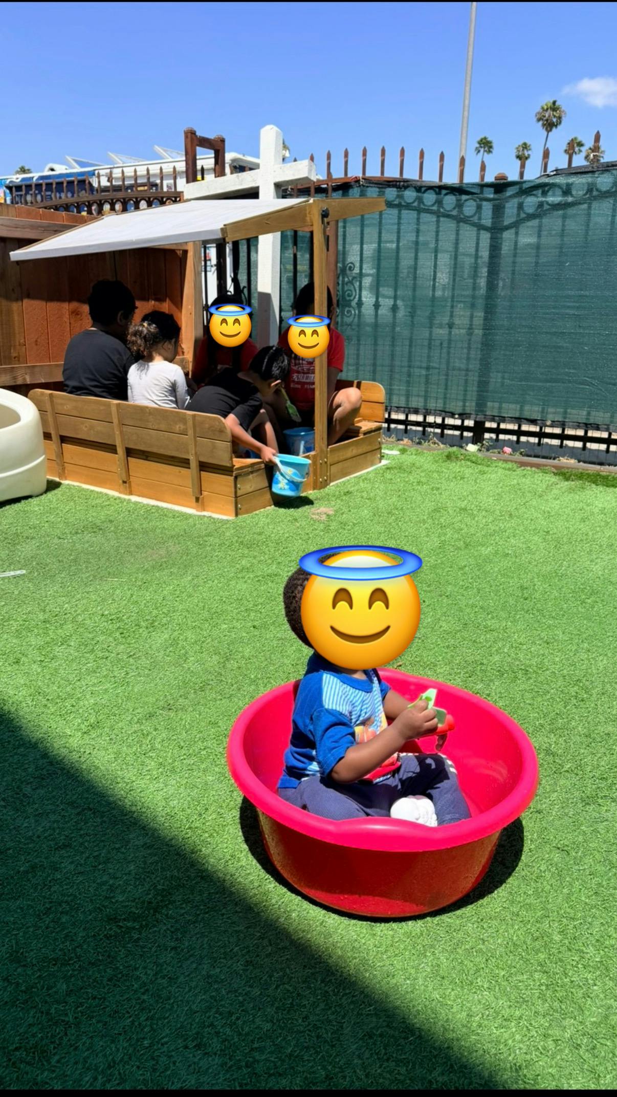 Children playing in a sandbox and a plastic tub on a sunny day