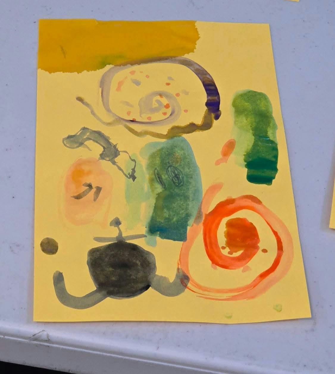 Child's painting with abstract shapes and swirls on yellow paper