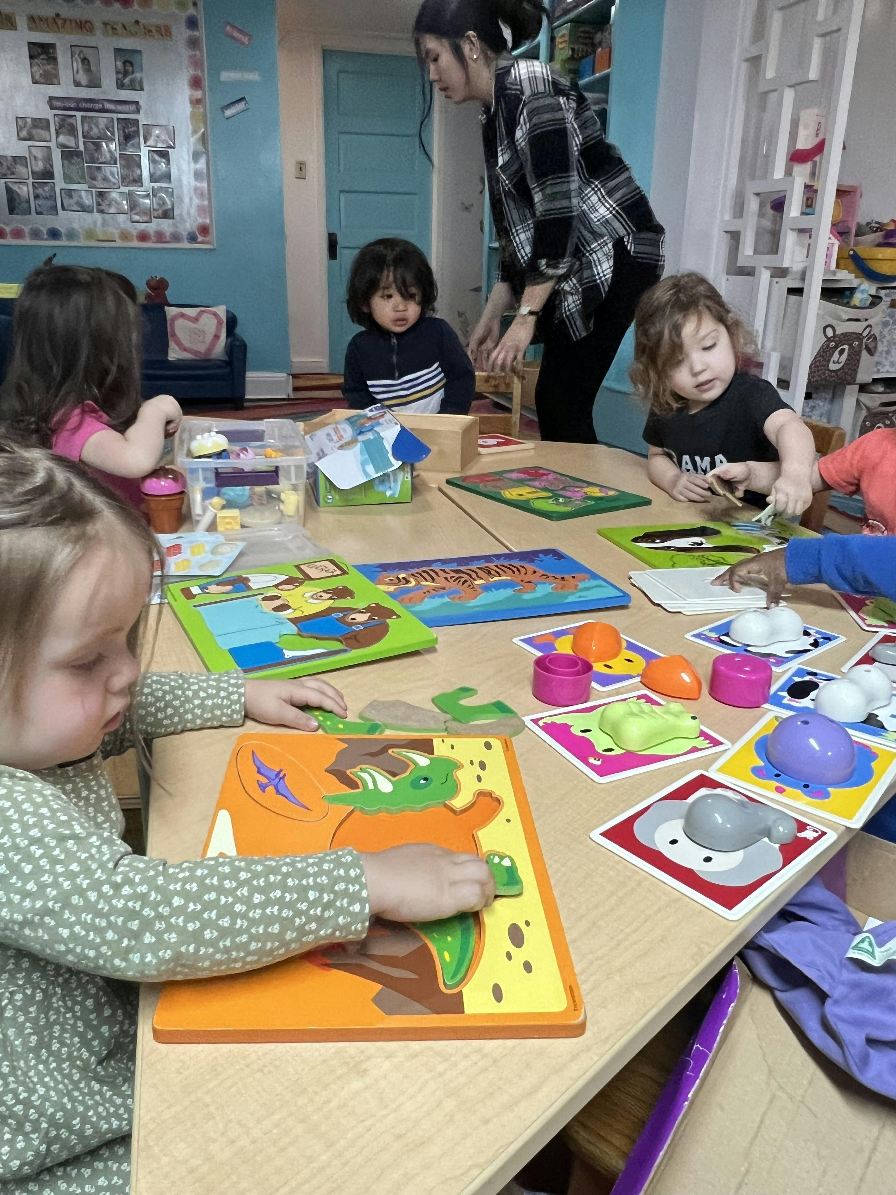 A person and multiple children working with puzzles and toys at a table