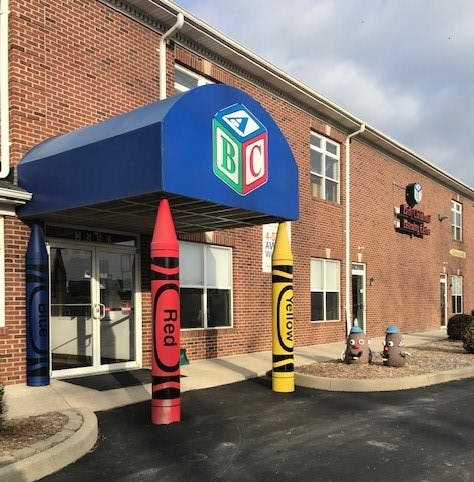 Building entrance with blue awning and large crayon decorations