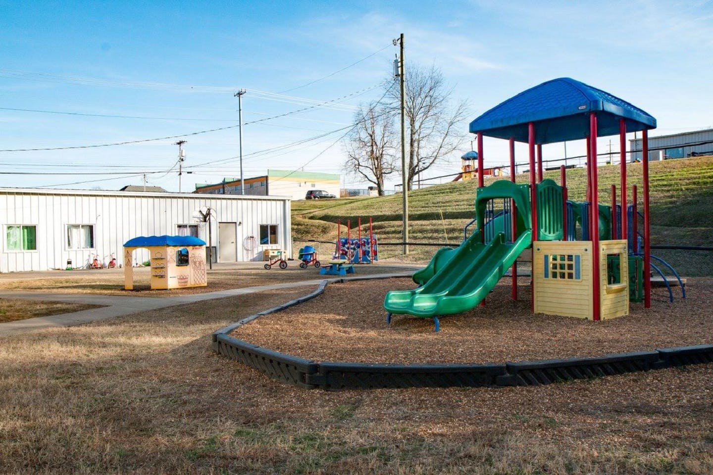 Empty outdoor playground with slides and play structures near a building