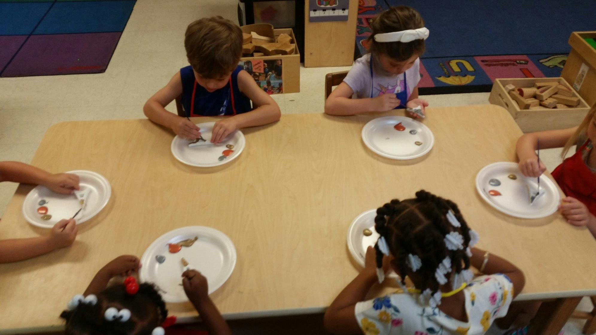 Children at a table with plates and small objects