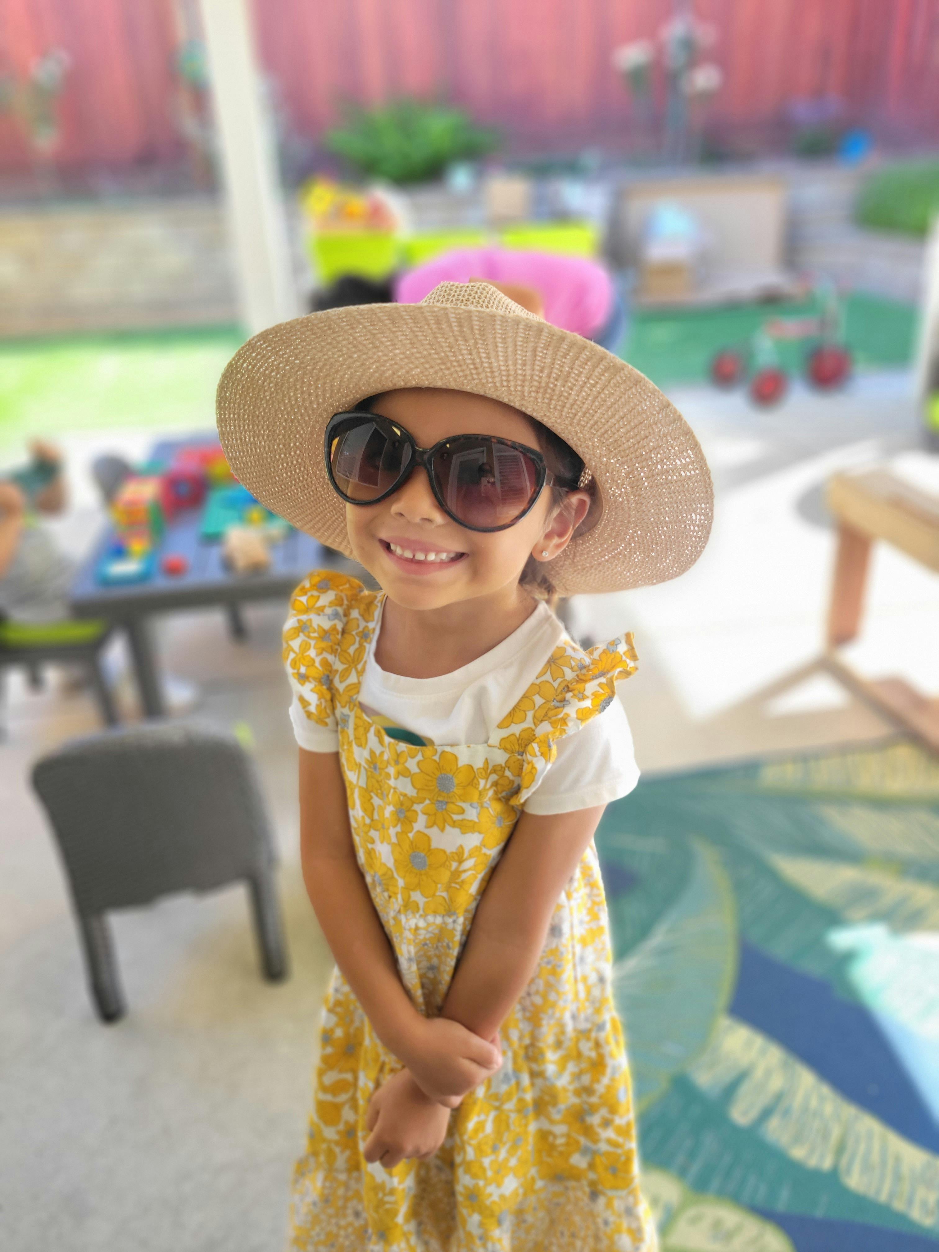 Child wearing a straw hat and sunglasses