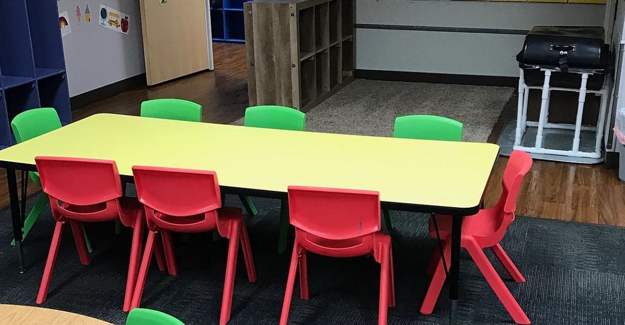 Yellow table with red and green chairs in a classroom