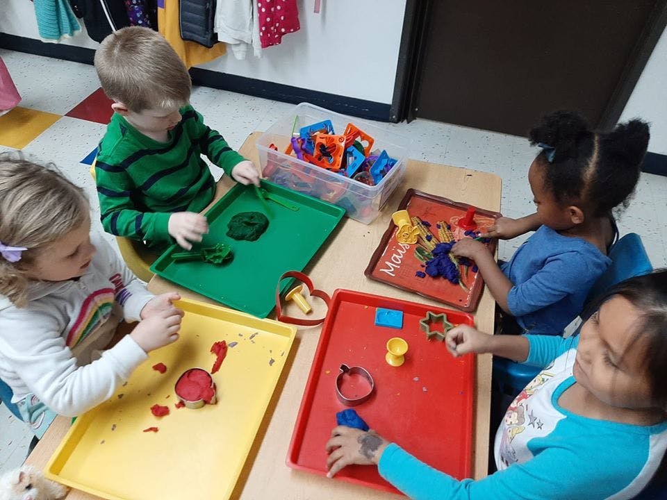 Four children playing with modeling clay at a table