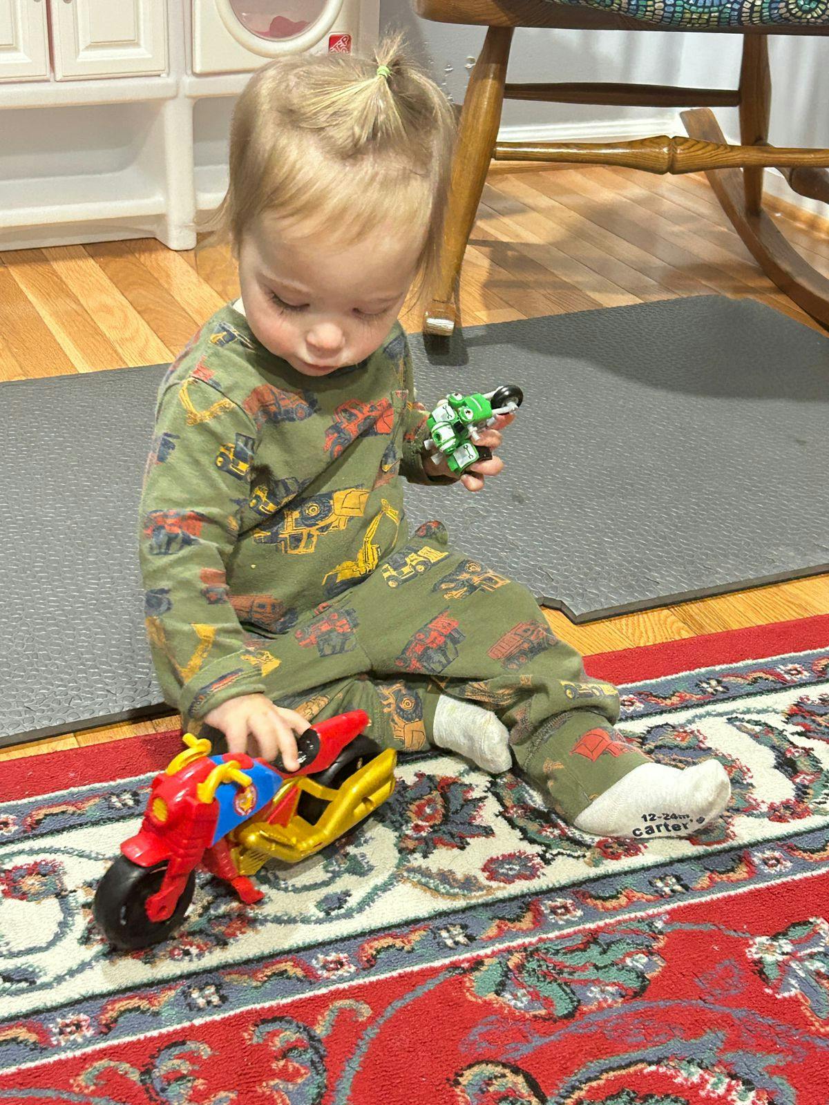 Child playing with toy motorcycles on a rug