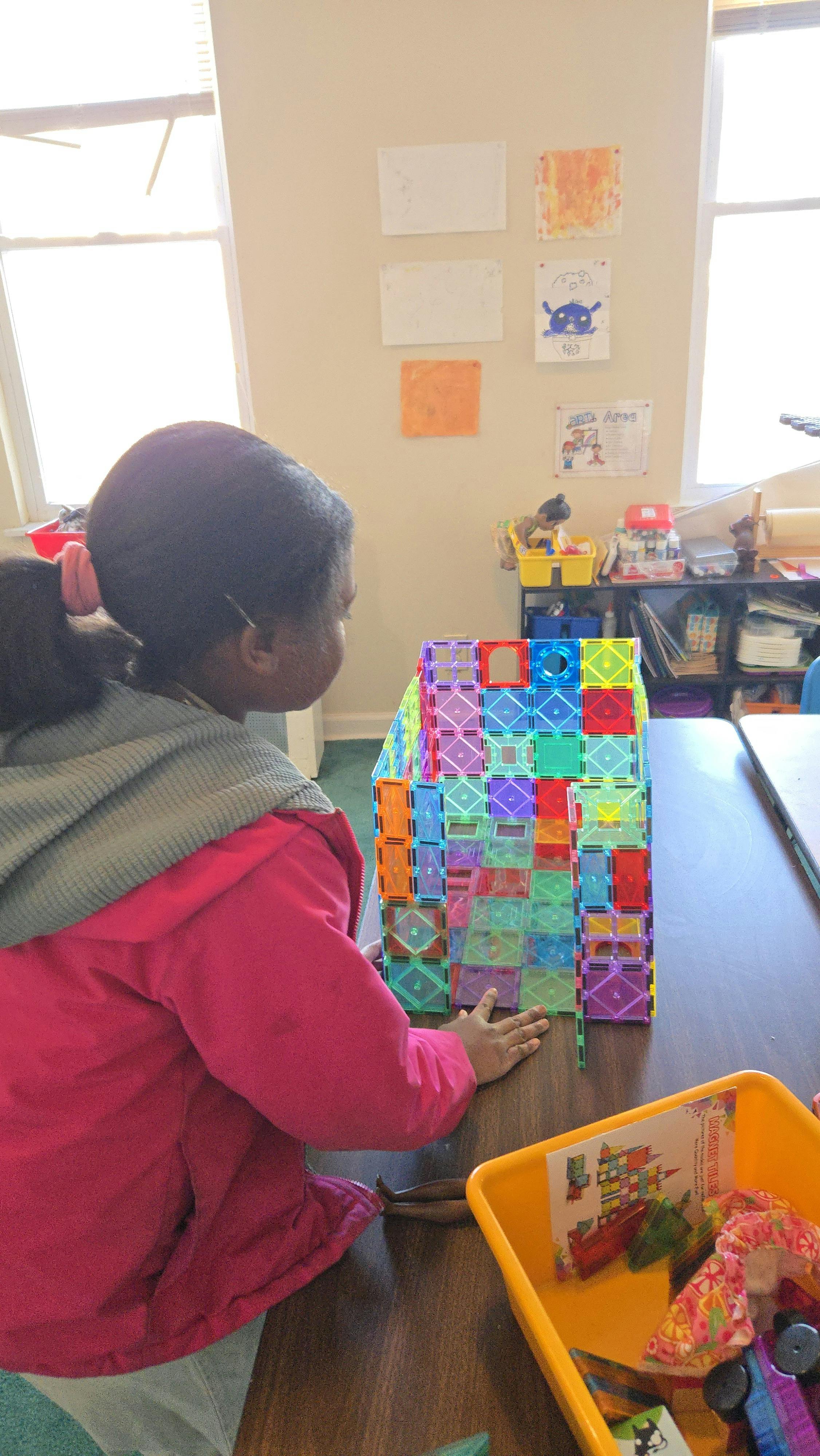 Child building a structure with colorful magnetic tiles on a table