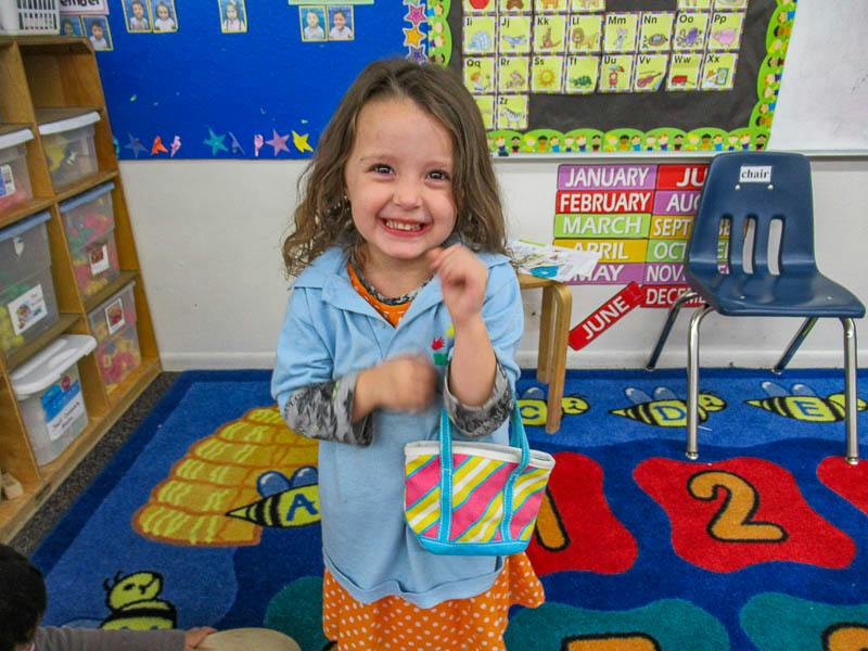 Child holding a small bag in a classroom