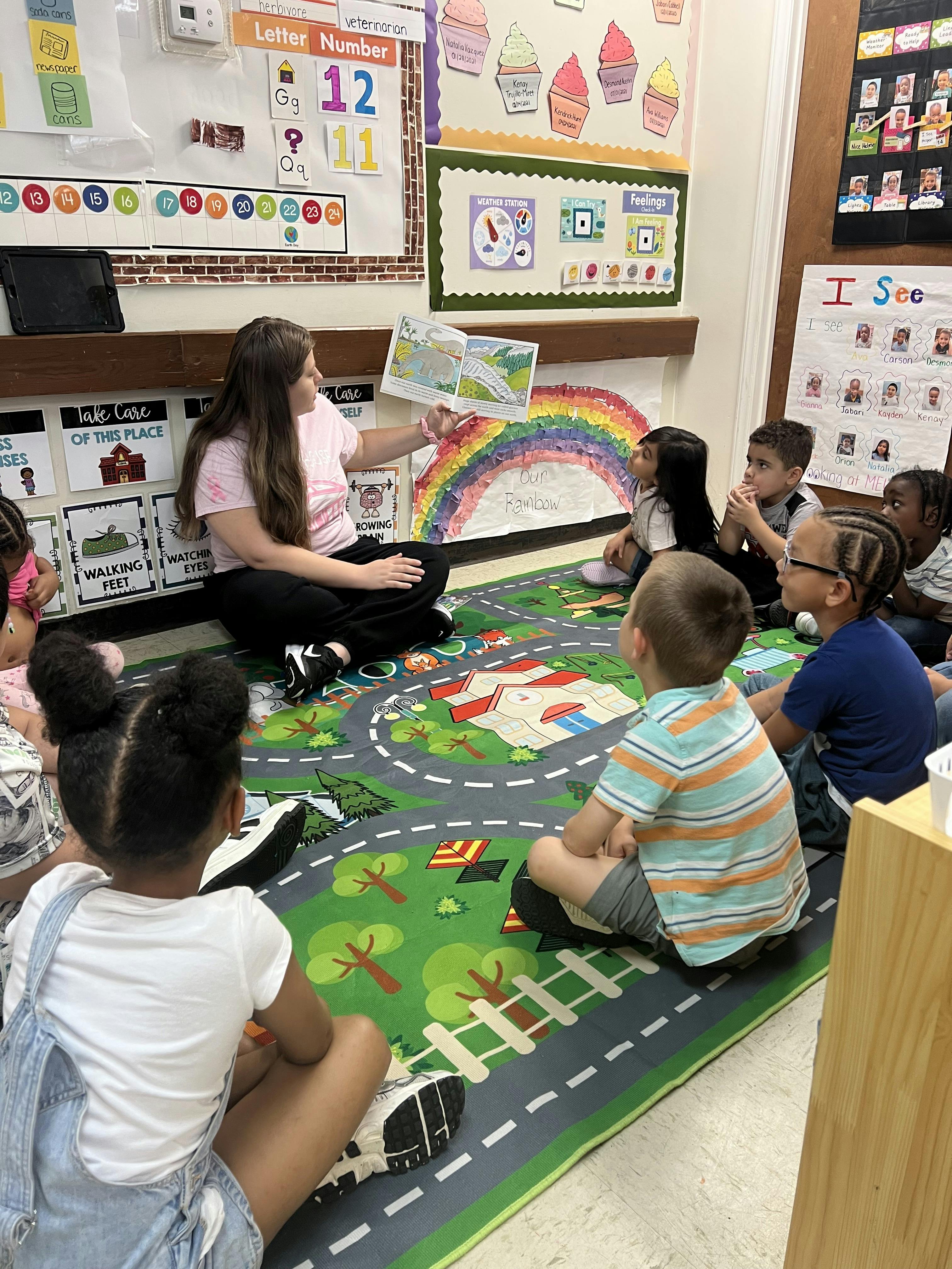 Adult reading a book to children in a classroom