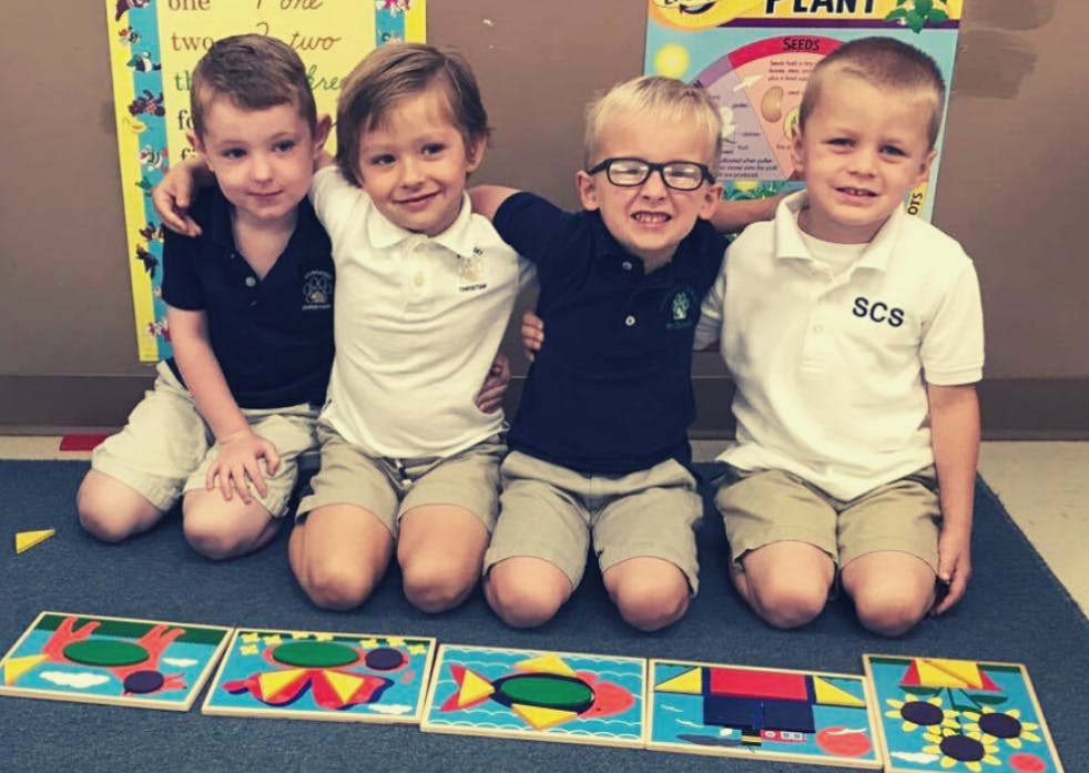 Four children kneeling with arms around each other, puzzles on floor