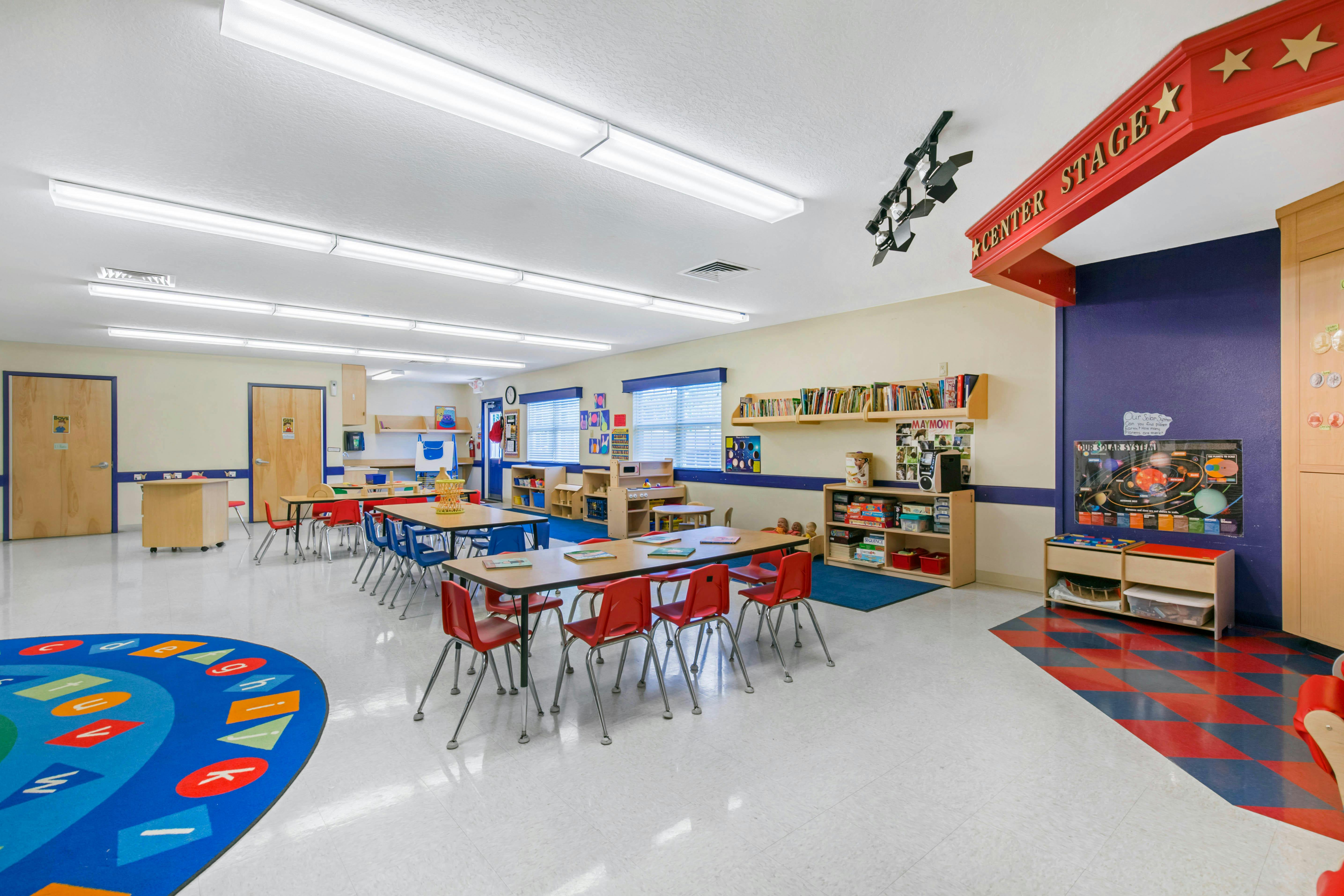Classroom with tables, chairs, and a colorful rug