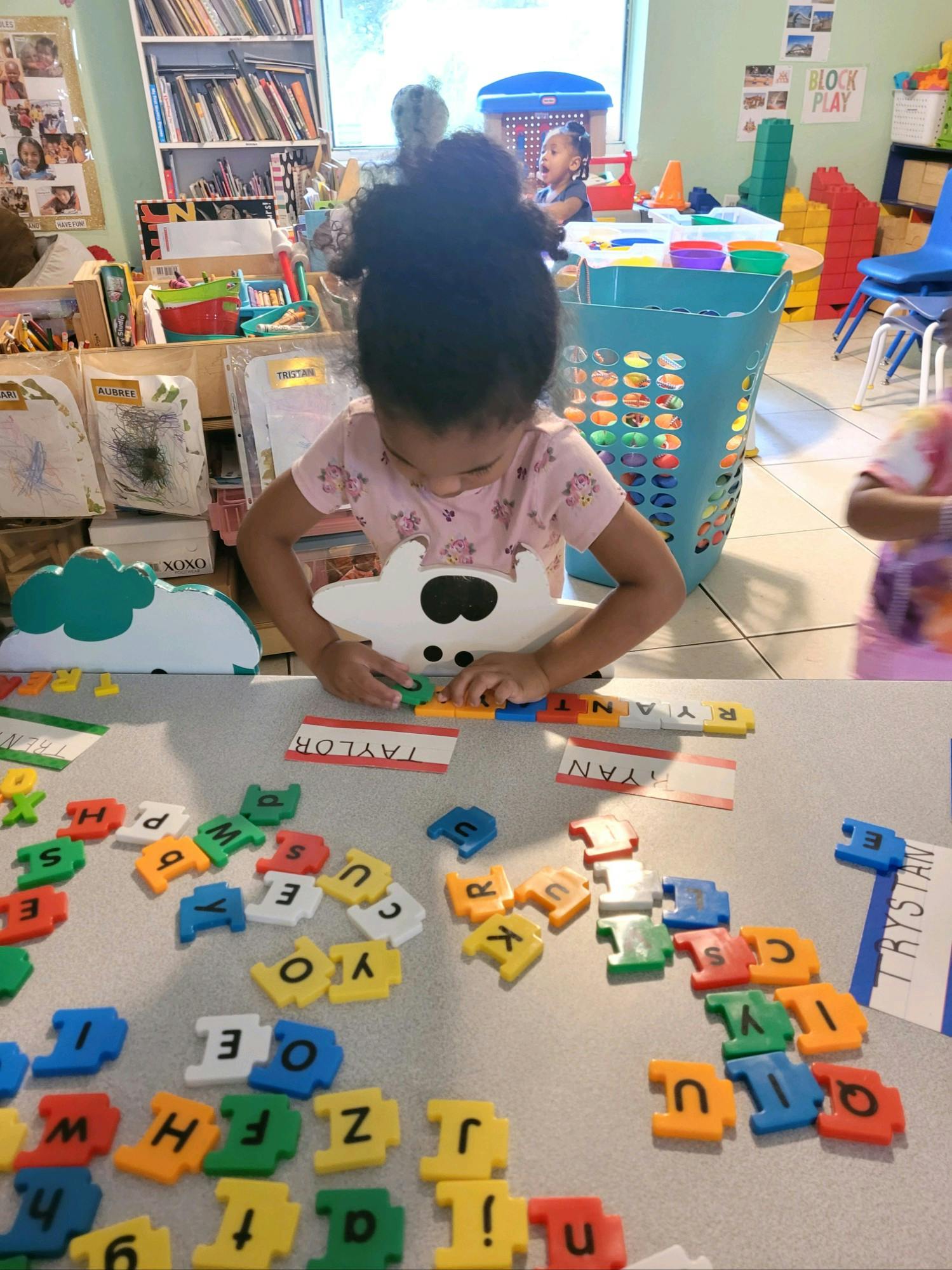 Child playing with colorful letter tiles on a table