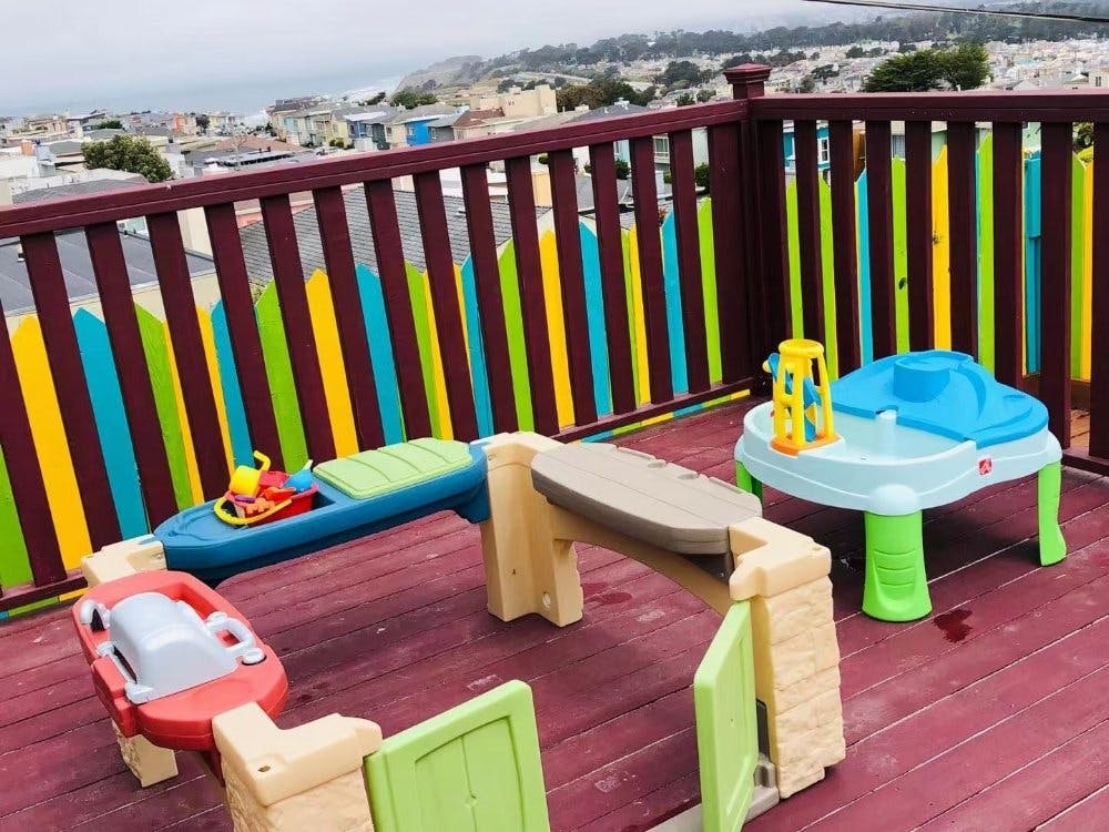 Children's play equipment on a deck with a colorful fence
