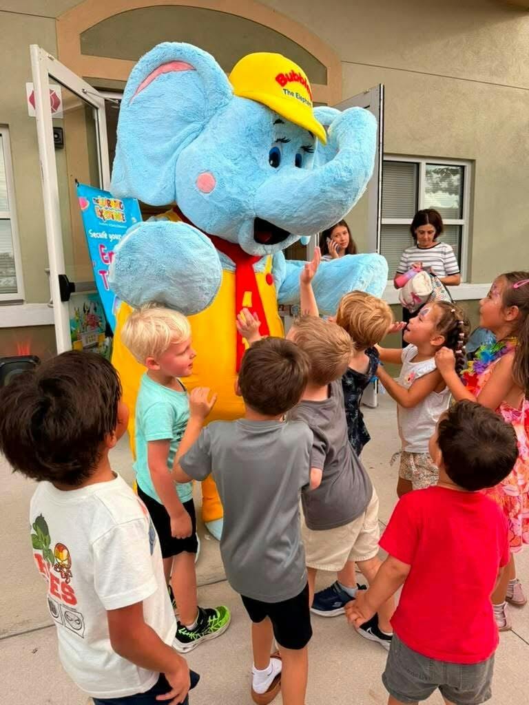 Group of children greeting a blue elephant mascot