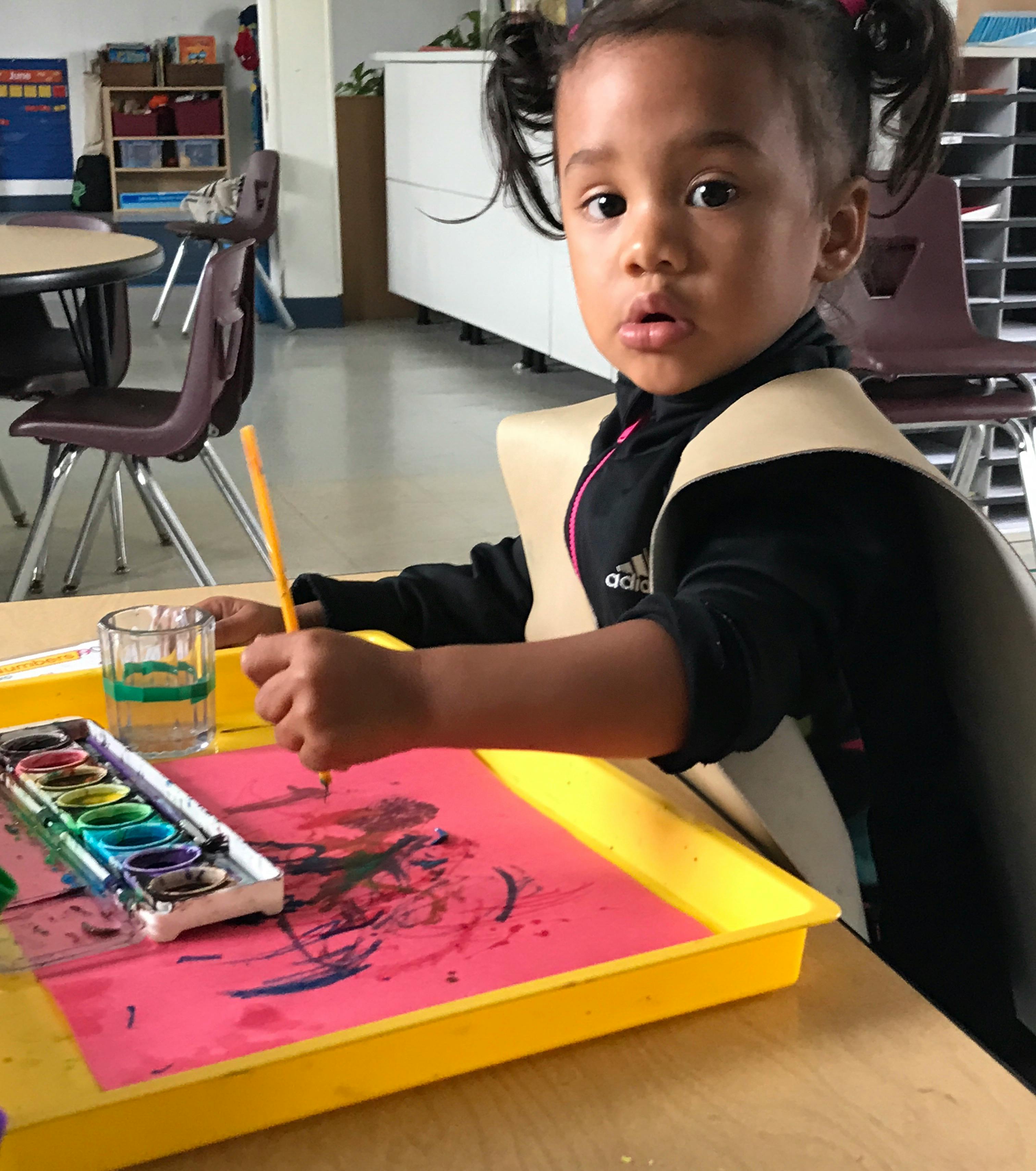 Child painting with watercolors in a classroom