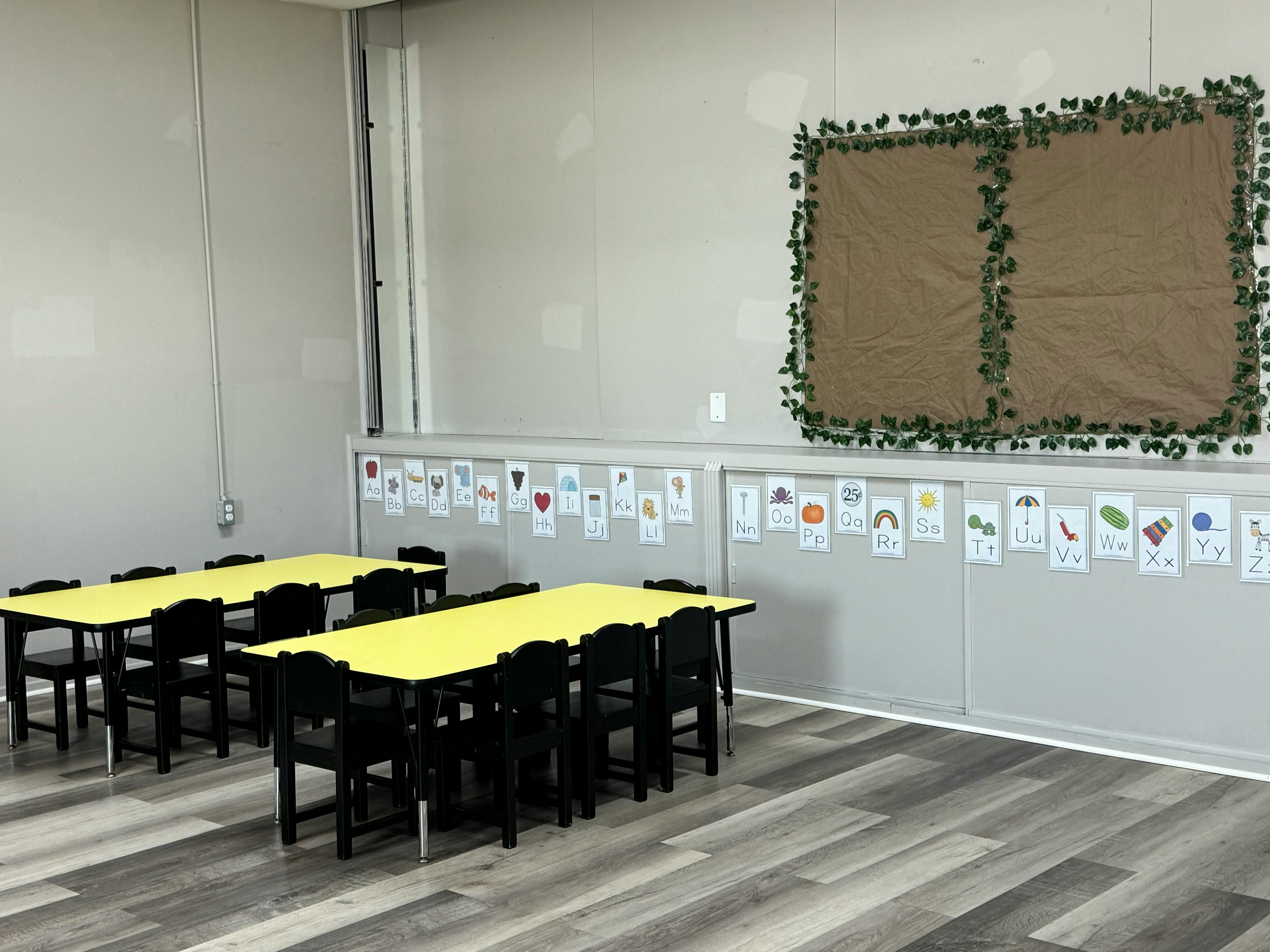 Classroom with two yellow tables and black chairs