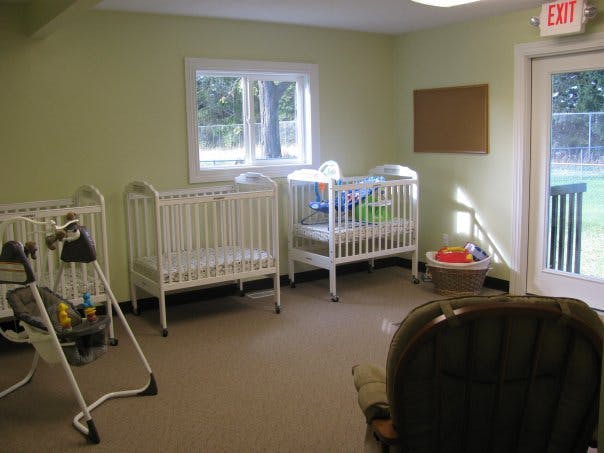 Three cribs and a baby swing in a room with light green walls