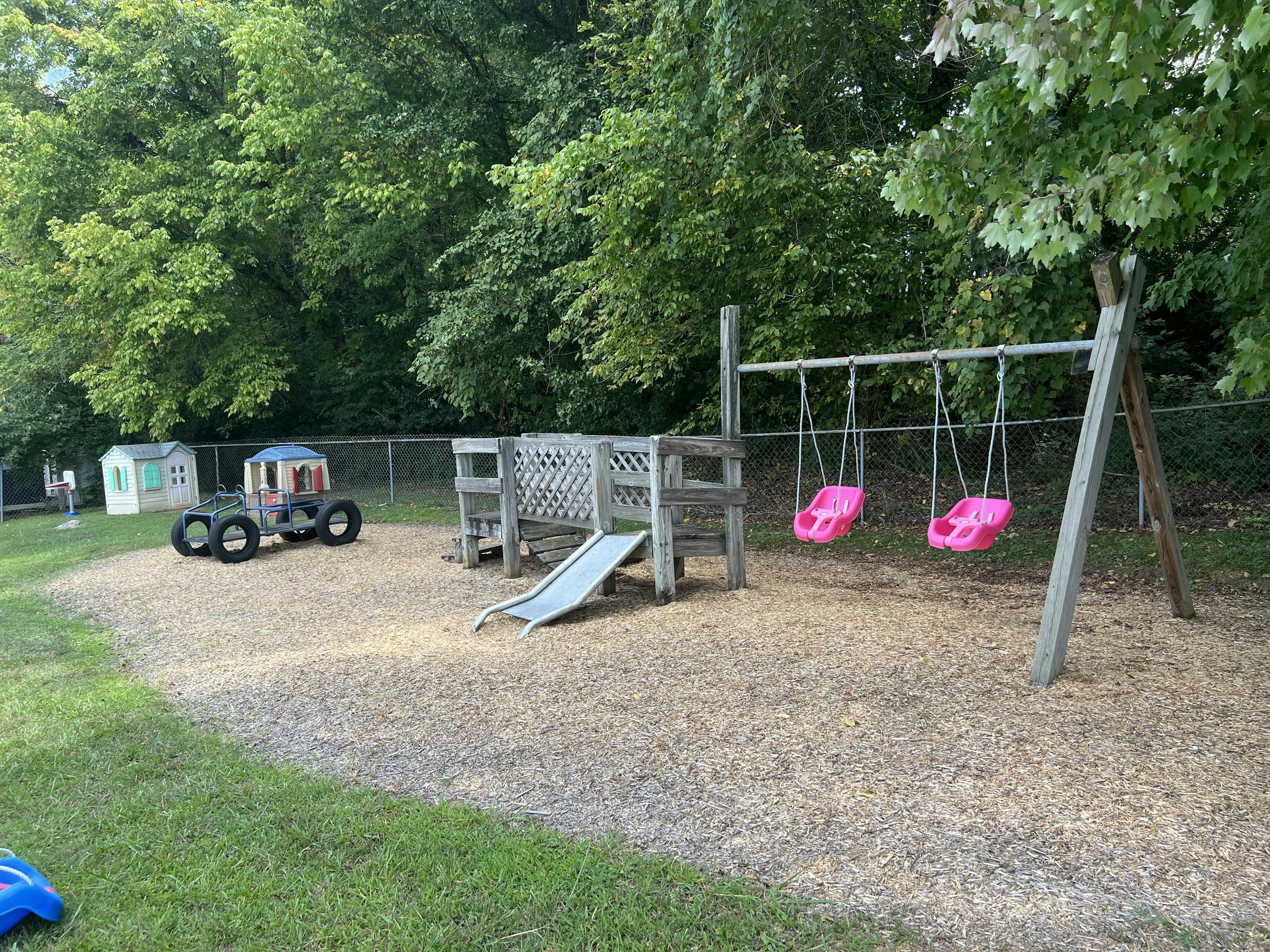 Playground with a wooden play structure, slide, and swings