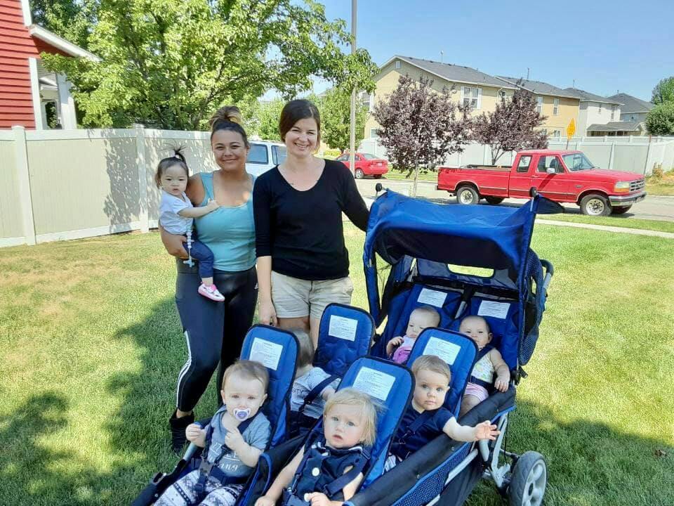 Two people with a child and a multi-seat stroller with several children