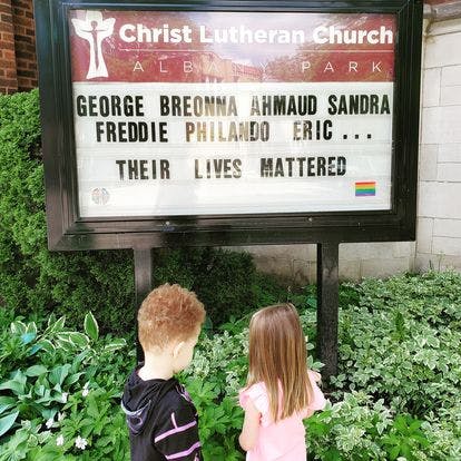 Two children looking at a church sign that reads "Their Lives Mattered"
