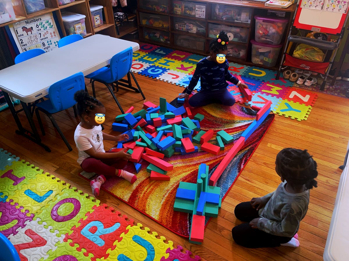 Three children playing with colorful building blocks on a rug in a room