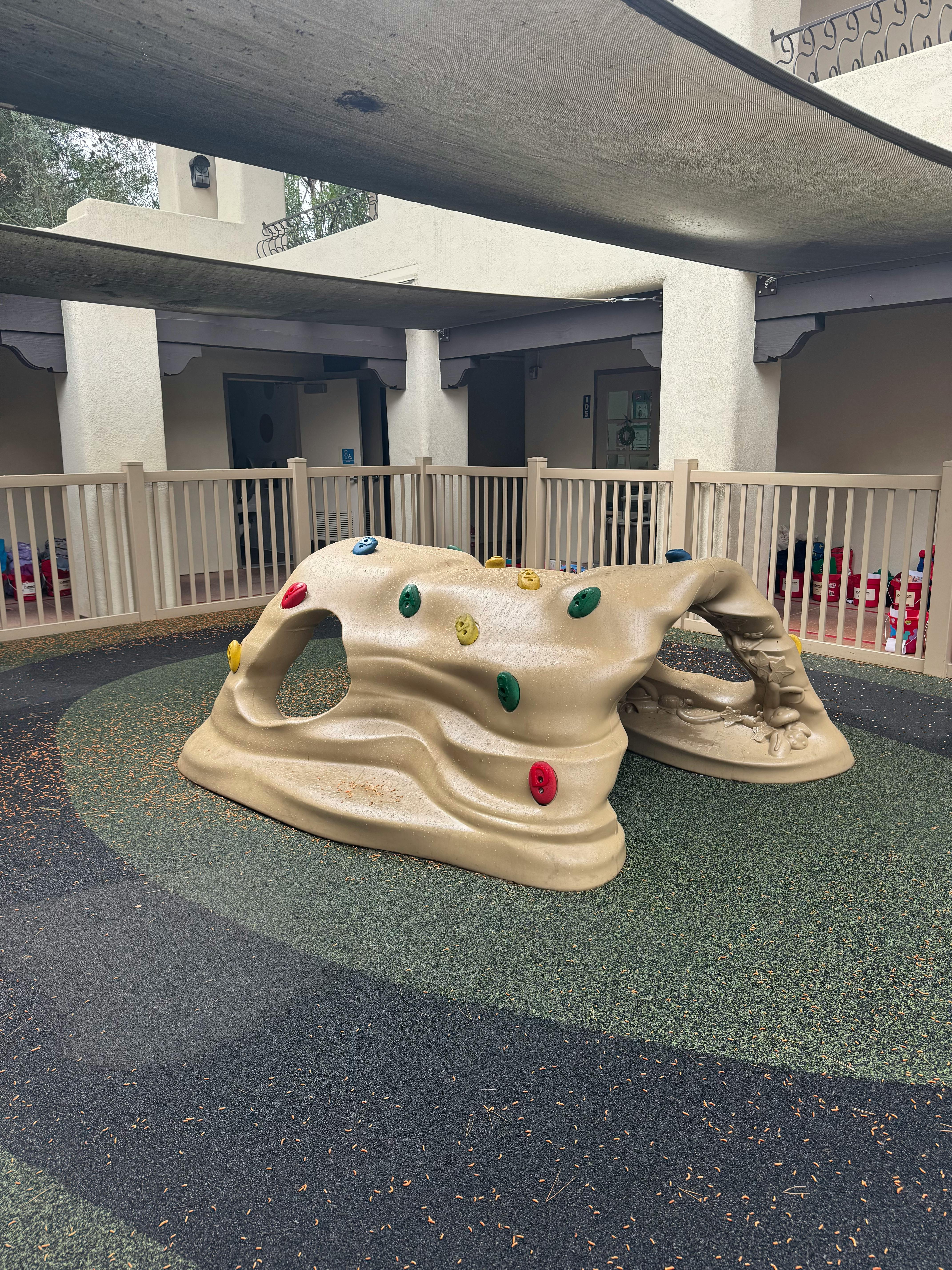 Playground climbing structure with colorful holds on a soft surface
