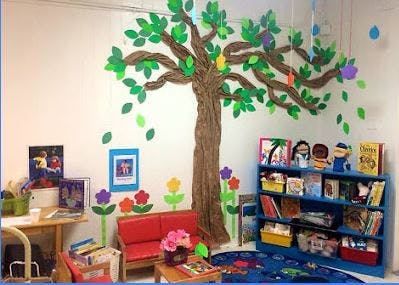 Classroom with a tree mural, red seating, and a blue bookshelf