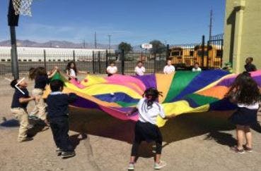 Children playing with a colorful parachute outdoors