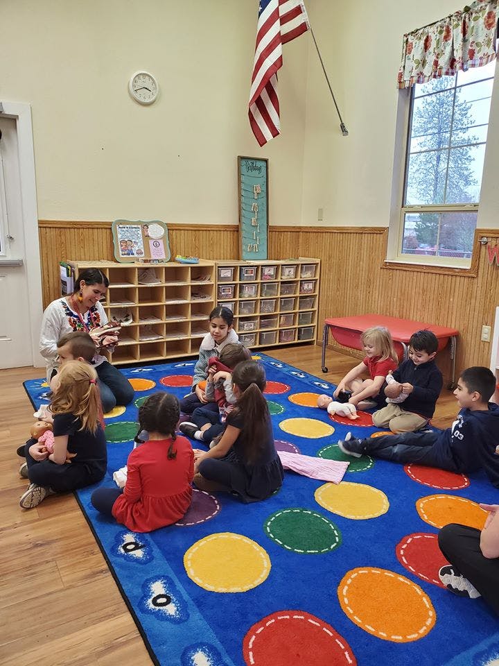 Adult reading to children sitting on a colorful rug in a classroom