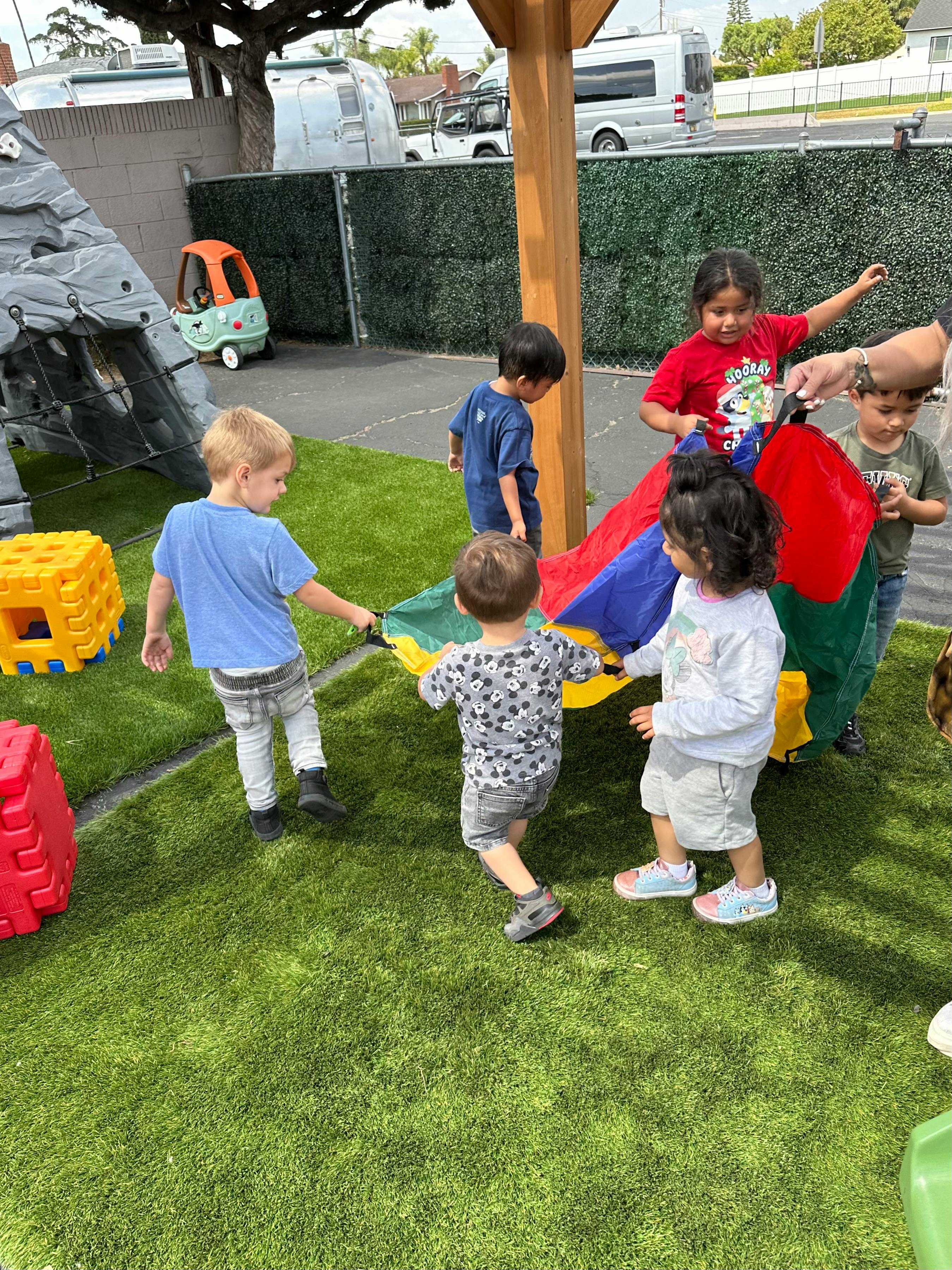 Children playing with a colorful parachute on a grassy area