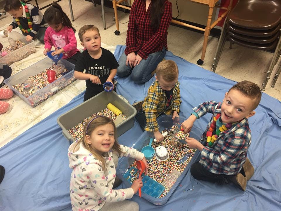 Children playing with sensory bins filled with small objects