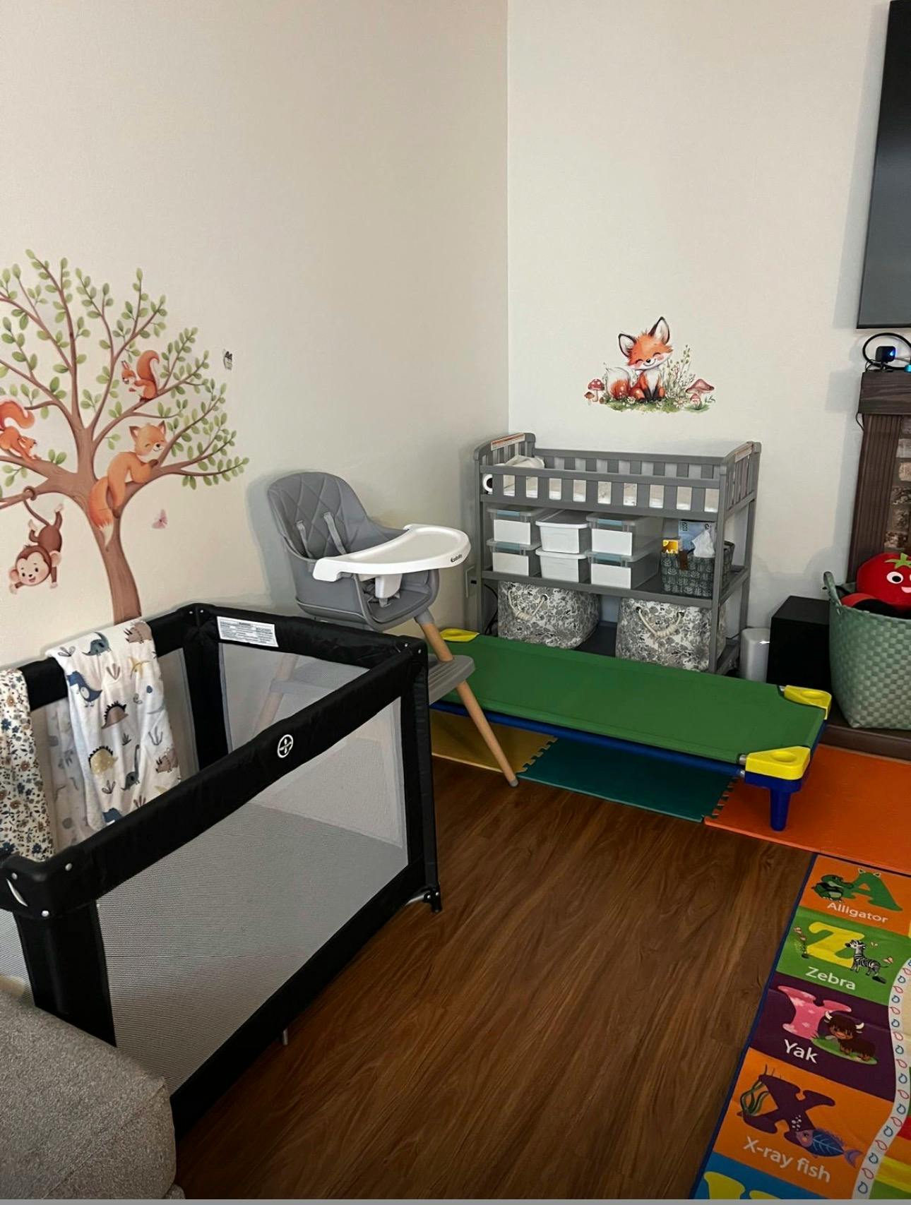 Child's room with a playpen, high chair, changing table, and cot