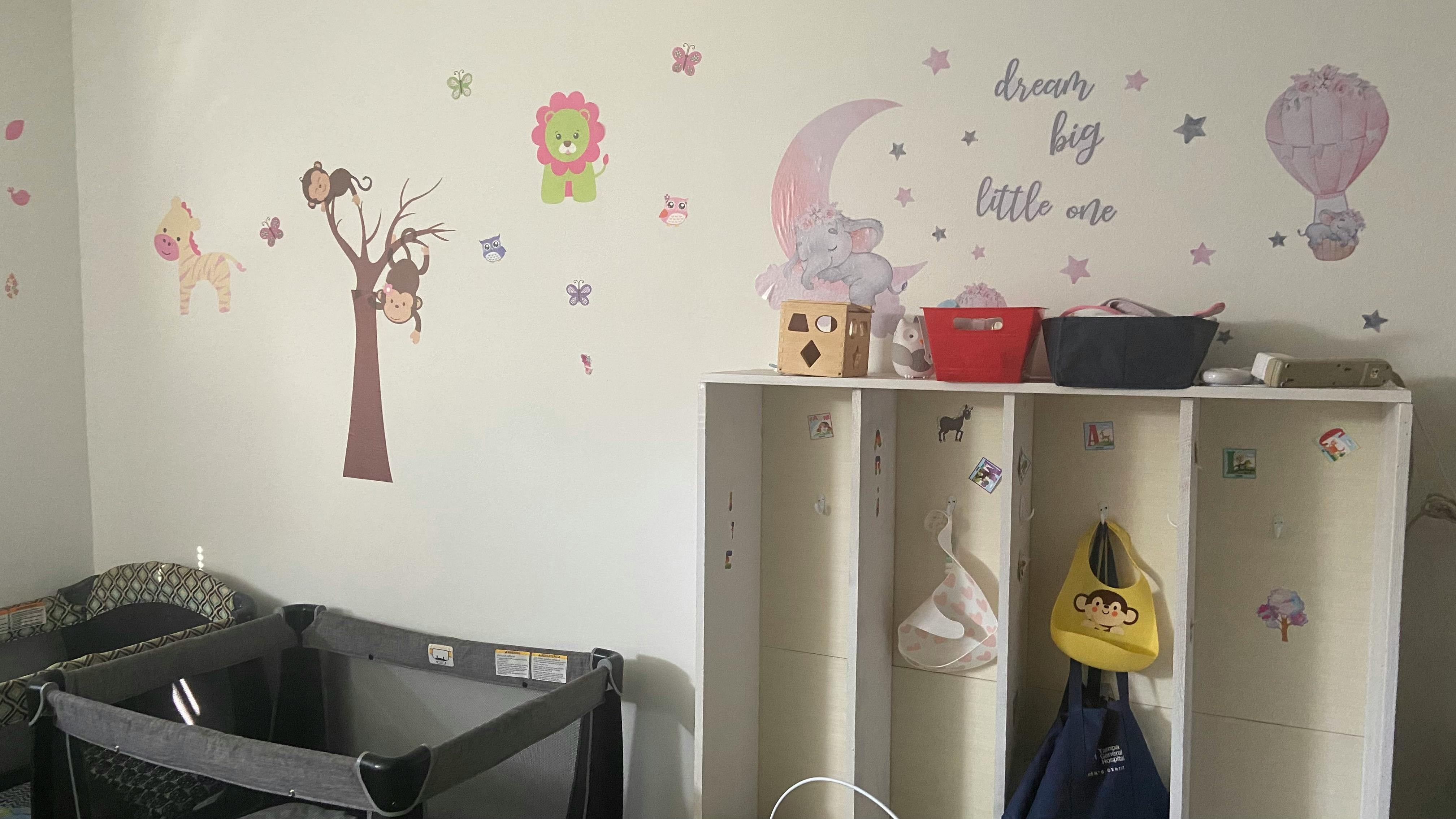 Nursery room with a crib and wall decals of animals and text