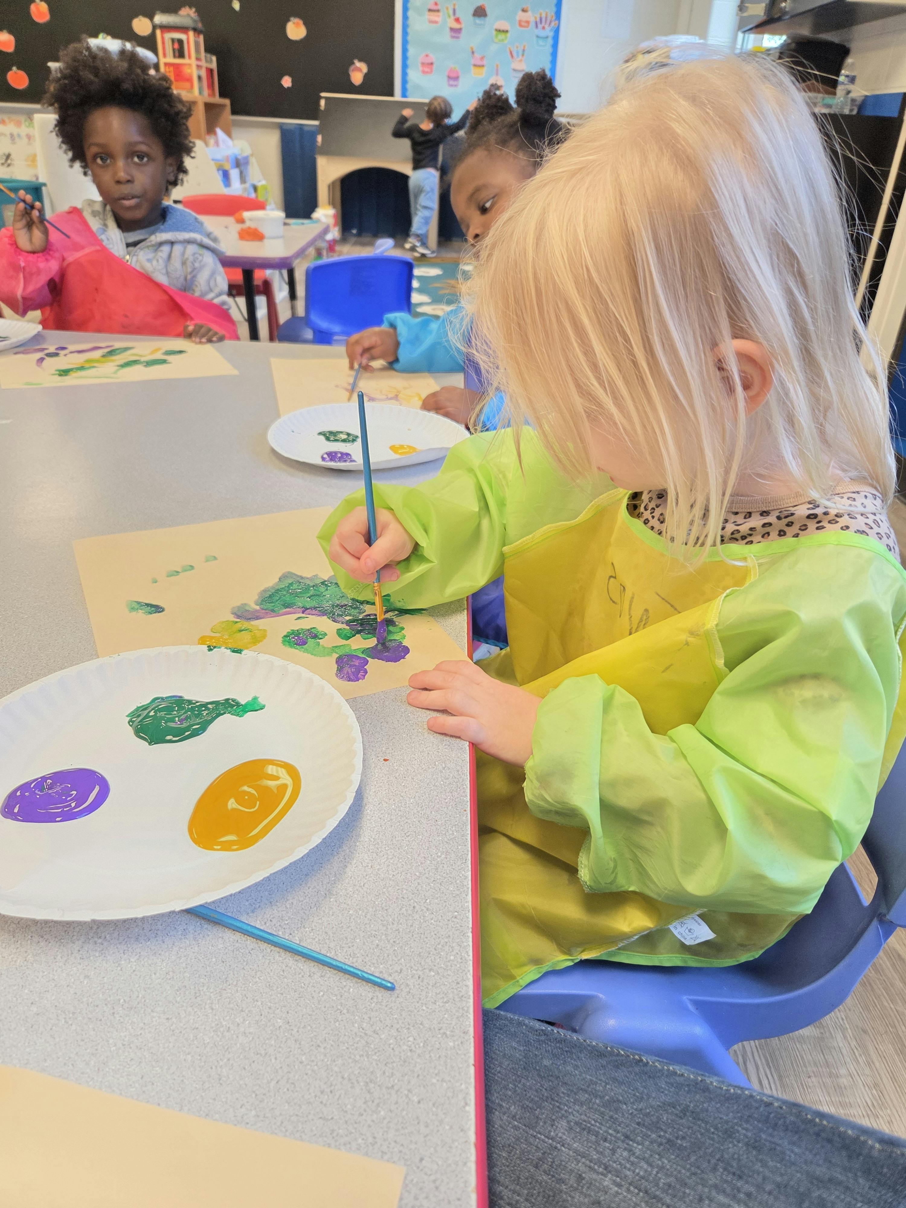 Children painting at a table in a classroom