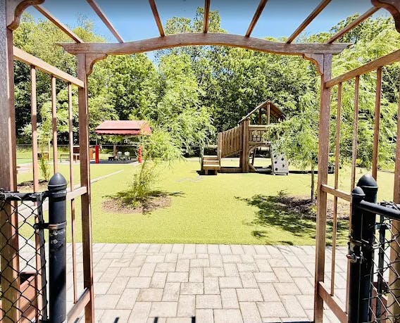 An outdoor playground with a wooden play structure and covered seating area