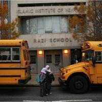 Two school buses parked in front of a building with a person standing between them