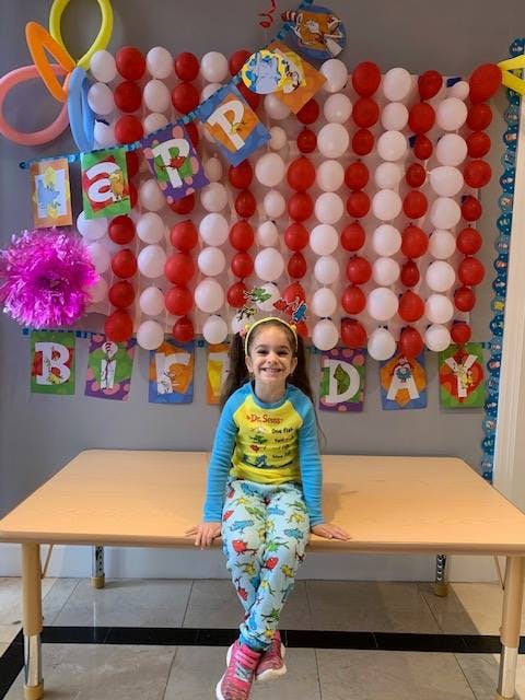 Child sitting on a table in front of a balloon and banner decoration