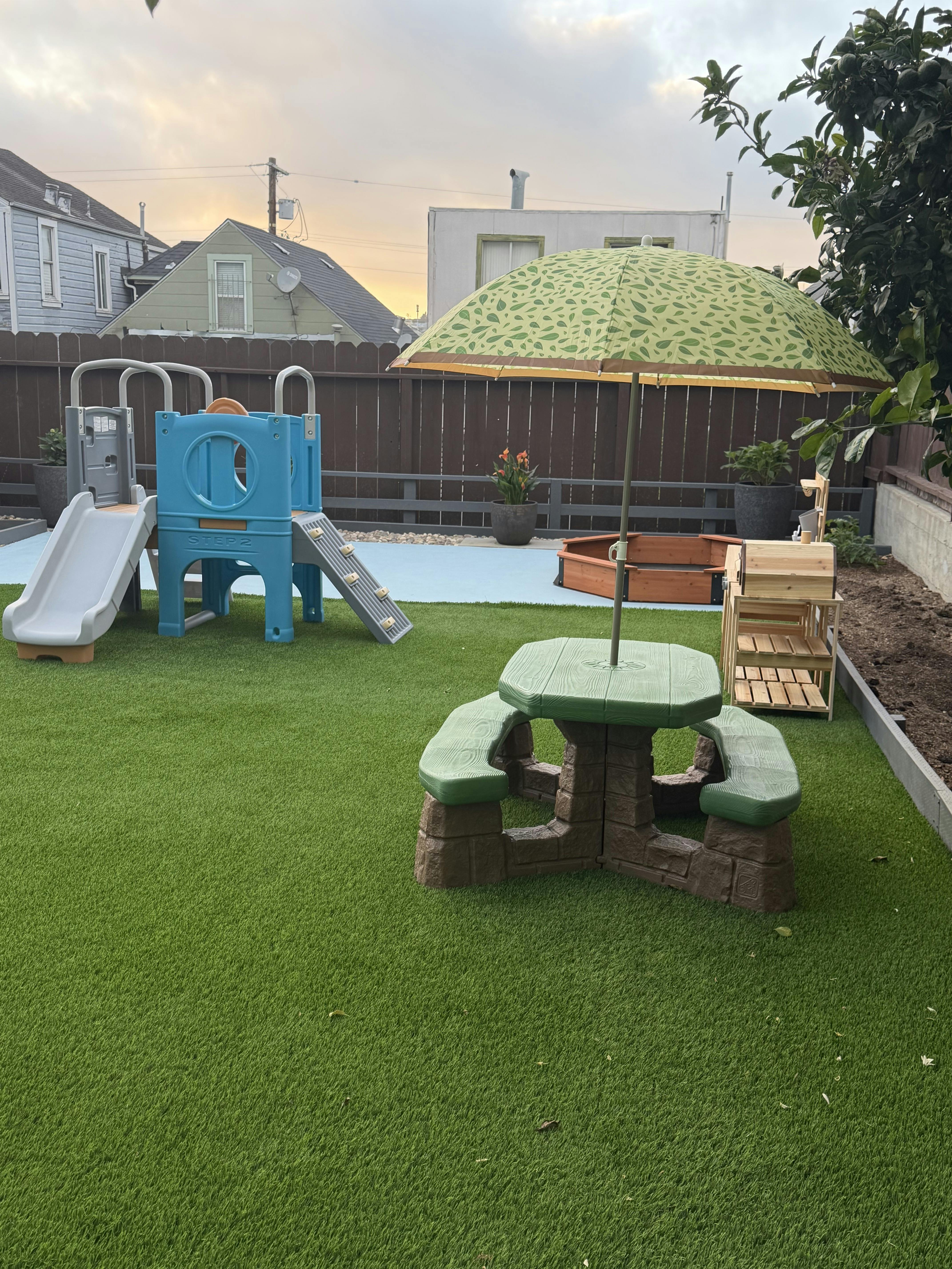 Backyard play area with a slide, picnic table, and sandbox