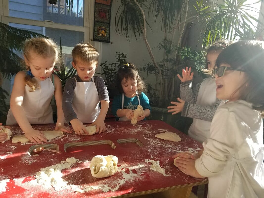 Children kneading dough on a red table