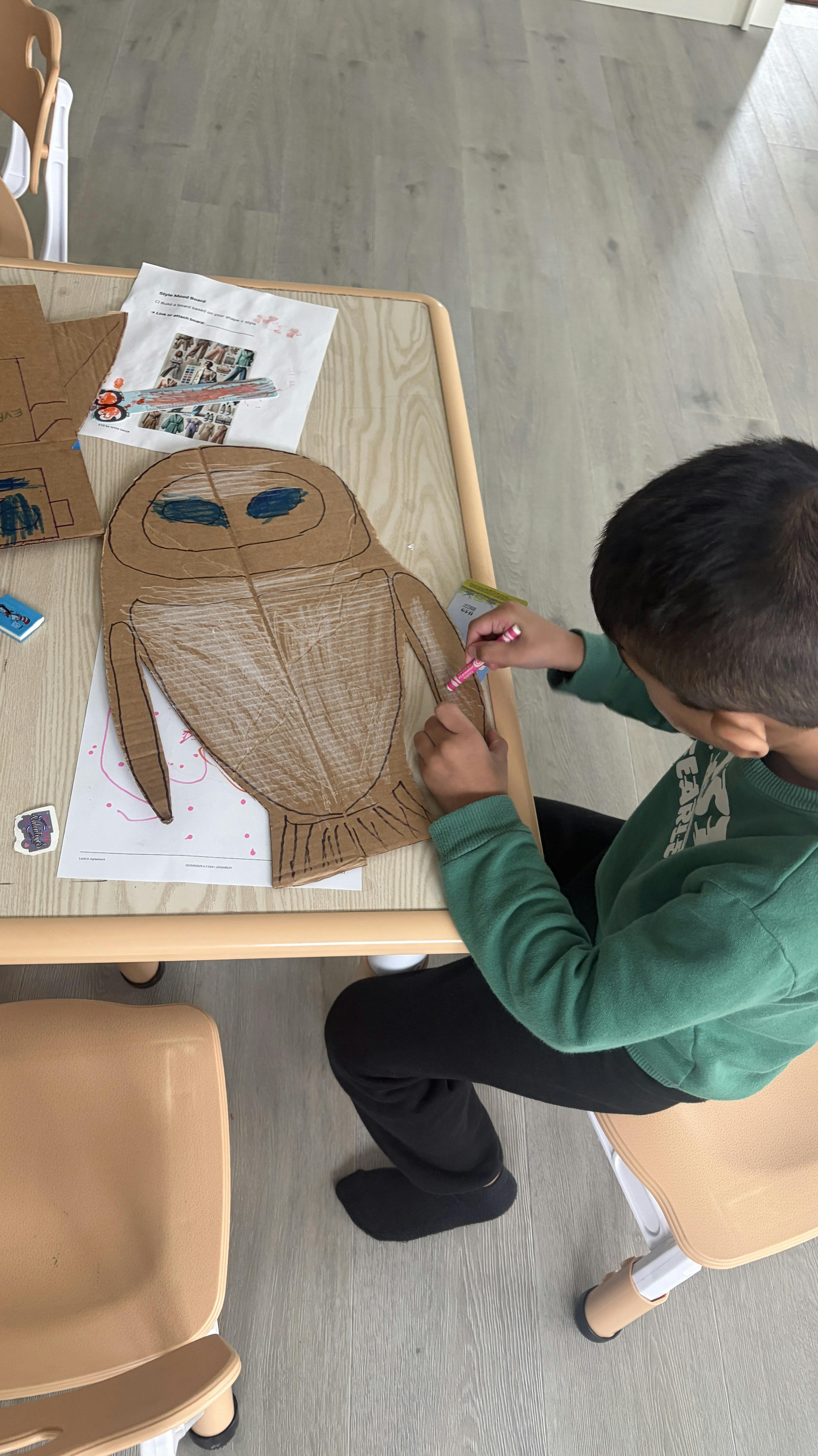 Child coloring an owl cutout at a table