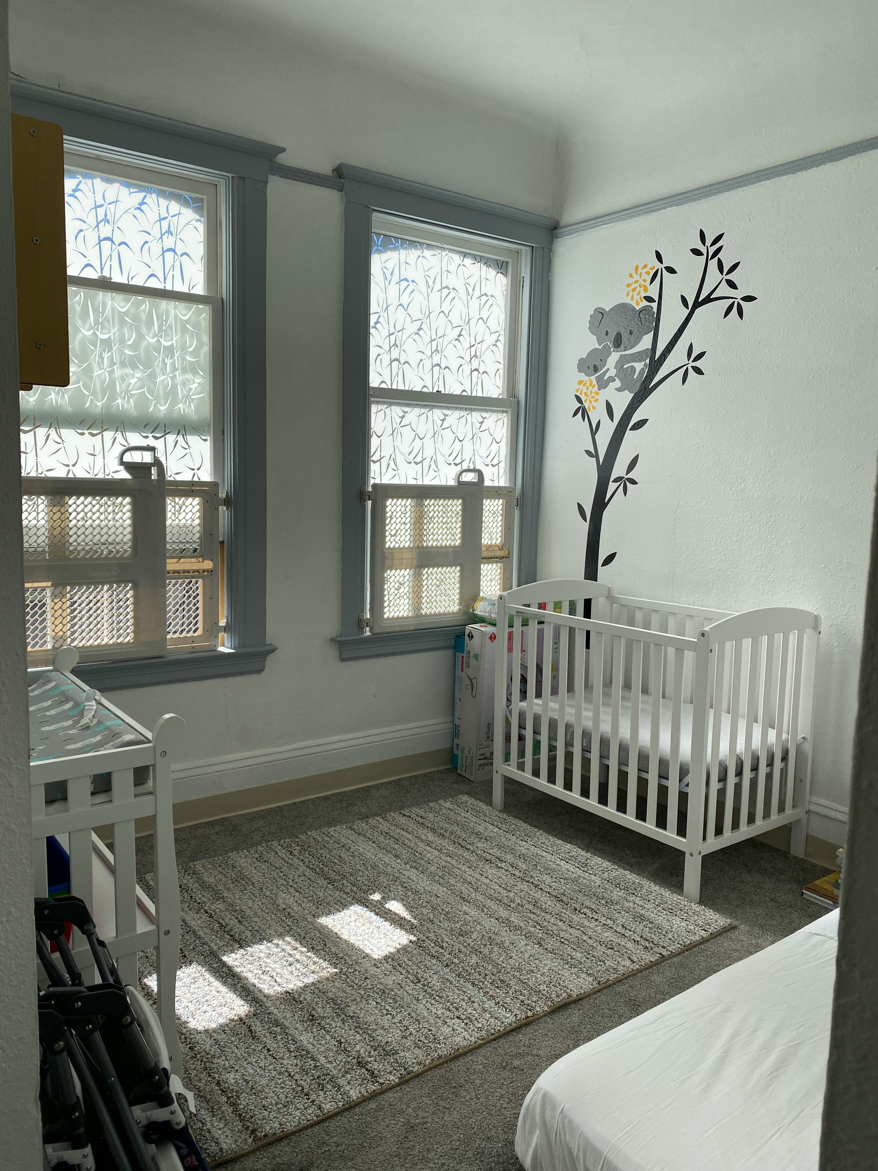 Nursery room with a white crib, changing table, and koala wall decal